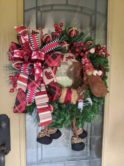 Plush Winter Moose in pine wreath form.  Large bow in red wired ribbons.
Red berries and picks.